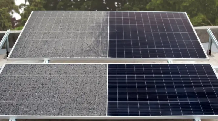 Solar panels half coated in dust and grime, half cleaned back to dark glass